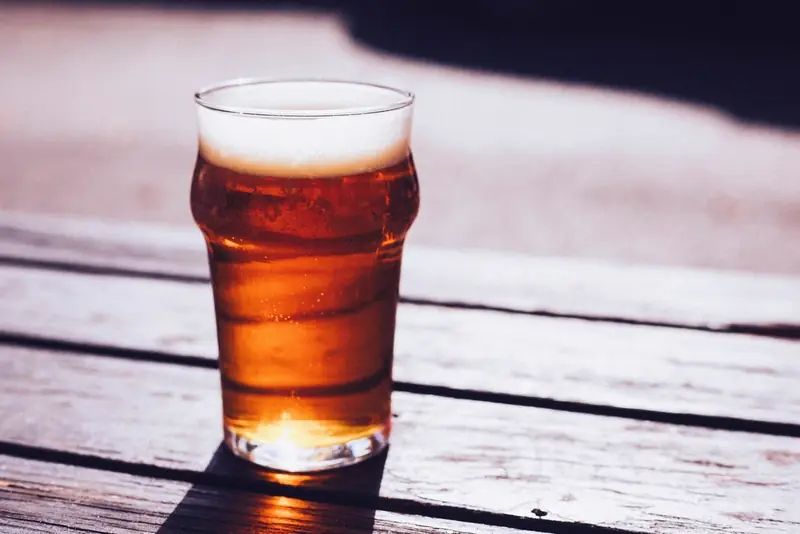A pint of amber beer on a wooden table