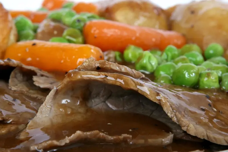 A roast dinner with carrots and peas